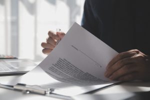 Asian businessman reviewing document reports at office workplace with computer laptop. legal expert, professional lawyer reading and checking financial documents or insurance contract